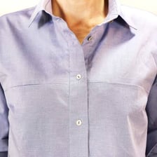 Buttons fastened through buttonholes on a shirt.