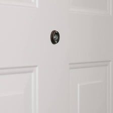 A close-up of a peephole installed in a door.