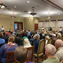 Community members sit together at a public meeting.