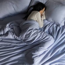 A bedspread covering a bed while a person lies beneath it