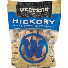 Hickory wood chunks beside meat cooking in a smoker
