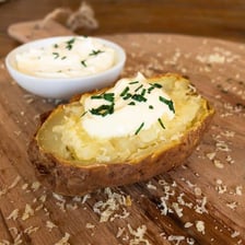 A baked potato topped with chopped green chives.