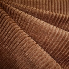 A close-up view of brown corduroy showing its raised parallel ribs