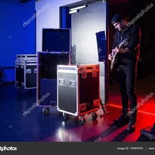 A concert crew member moving a guitar amplifier backstage