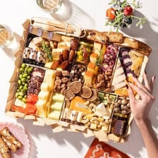 A serving board arranged with assorted cheeses and accompaniments.