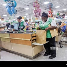 A grocery-store employee packing a customer’s purchases into bags at a checkout