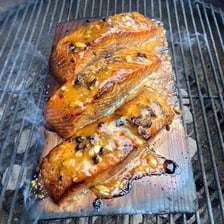 A salmon fillet cooked and presented on a cedar plank