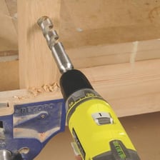 A power drill making a hole in a piece of wood.