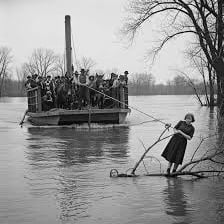 A ferryman guiding passengers across a river on a small ferry.