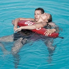 A lifeguard helping a swimmer out of the water