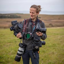 A photographer carrying professional cameras and photographic equipment