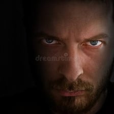 A person with a serious expression in a subdued setting.
