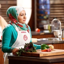 A cooking competition contestant preparing food in a professional kitchen.