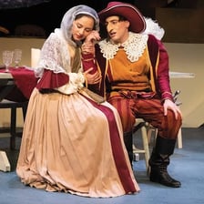 A theatrical scene depicting Cyrano de Bergerac speaking with Roxane