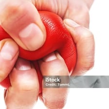 A hand compressing a soft stress ball.