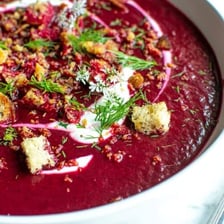 Whole and sliced beetroot beside a bowl of red borscht