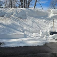 A large bank of windblown snow obstructing a winter road