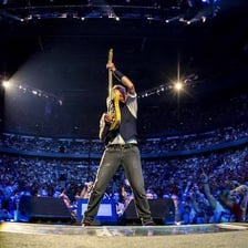 Bruce Springsteen performing onstage with a guitar.