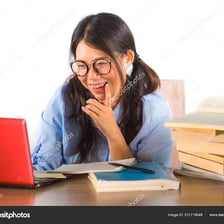 A studious student wearing glasses and working near books and a computer.