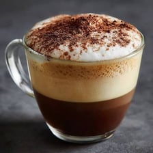 A cappuccino in a cup topped with frothy steamed milk.