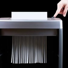 An office paper shredder cutting sheets of paper into strips.