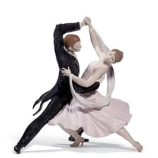 A formally dressed couple performing a foxtrot in a ballroom