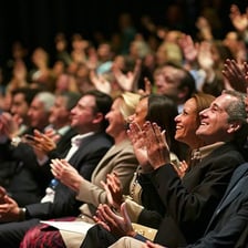 A person receiving applause from a large audience, illustrating broad admiration.