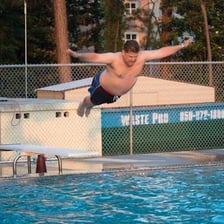 Divers performing a jackknife and a belly flop into a swimming pool.