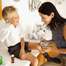 A mother applying a bandage to a child’s injured knee