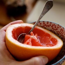 A halved grapefruit with a spoon beside the exposed citrus segments
