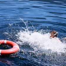 A person in the water beside a boat after going overboard.