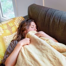 A person lying still and resting on a sofa