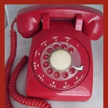 A hand turning the dial of a rotary telephone