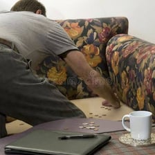 A person searching couch cushions for spare coins