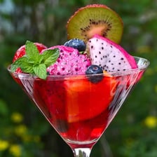 A glass of fruit punch garnished with pieces of fresh fruit.