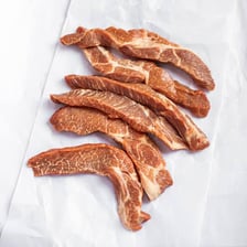 Small trimmed boneless pork rib cuts displayed by a butcher.
