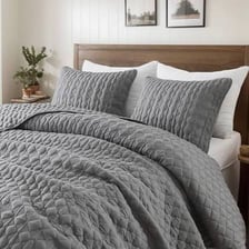 A bed covered with a quilt and duvet
