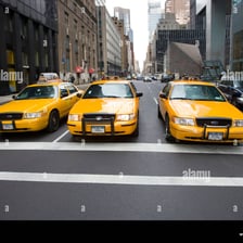 A taxi cab traveling on an urban street.