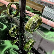 A metal object being coated with a thin layer during an electroplating process.