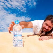 A person urgently reaching toward a glass of water