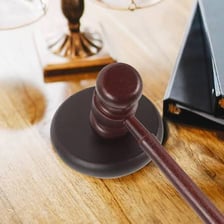 A wooden judge’s gavel resting on a courtroom desk