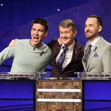 Contestants standing at podiums on the Jeopardy! quiz-show set.