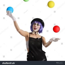 An entertainer juggling several colorful balls in the air.