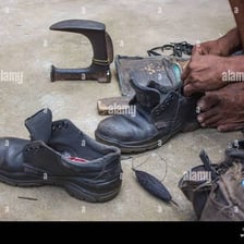 A cobbler repairing a leather shoe at a workbench