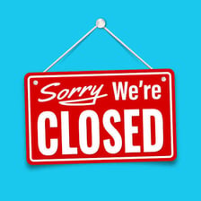 A storefront displaying a sign that the business is closed.