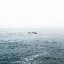 A small boat rising and falling on the surface of ocean waves.
