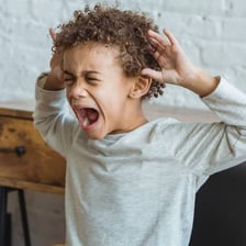 A child experiencing an emotional tantrum indoors