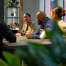 Several people engaged in a conversation around a table.