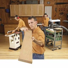 A woodworker sawing and planing boards in a workshop