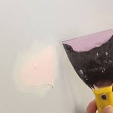 Spackle being applied to a small wall hole with a putty knife.